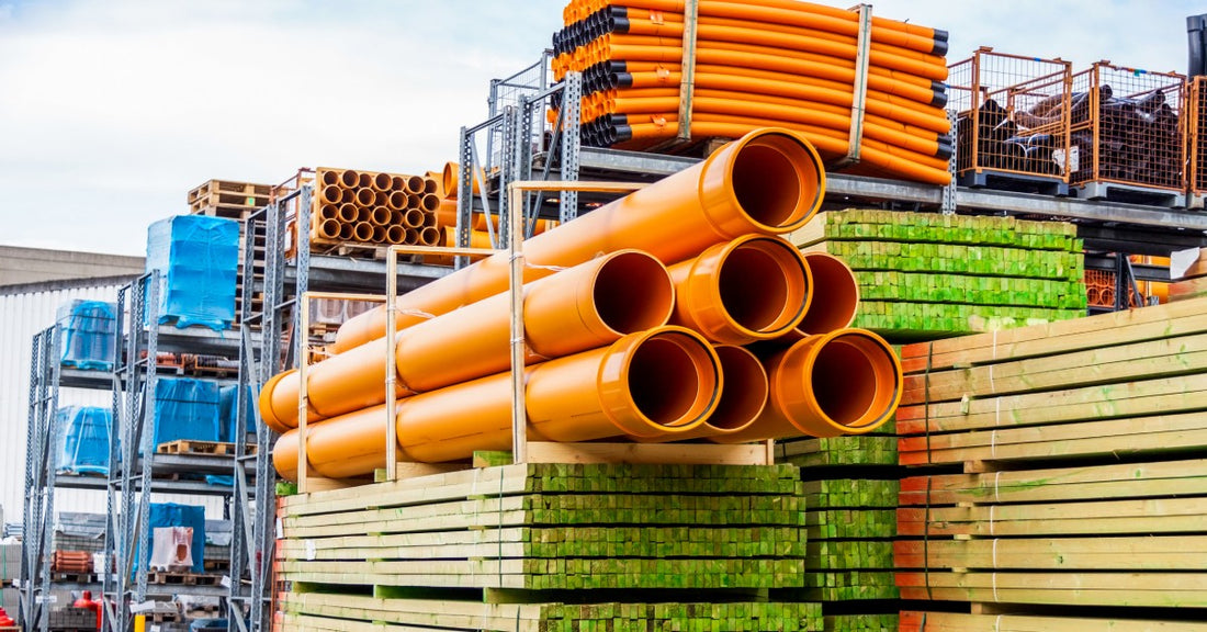 A group of large orange pipes stacked on top of each other in a yard. They have bars around them to keep them in place.