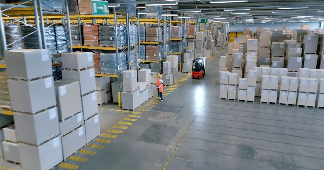  A busy cargo warehouse with workers moving between aisles. All of the boxes are neatly on either racks or shelves.