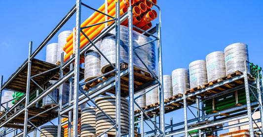 An outdoor logistical facility with well-organized construction supplies stacked on different levels.