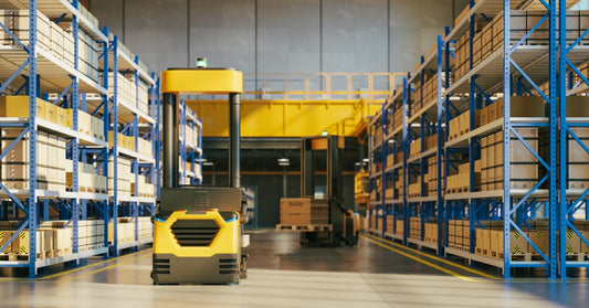 An autonomous robot moving through a warehouse aisle between tall racks filled with stacked cardboard boxes.