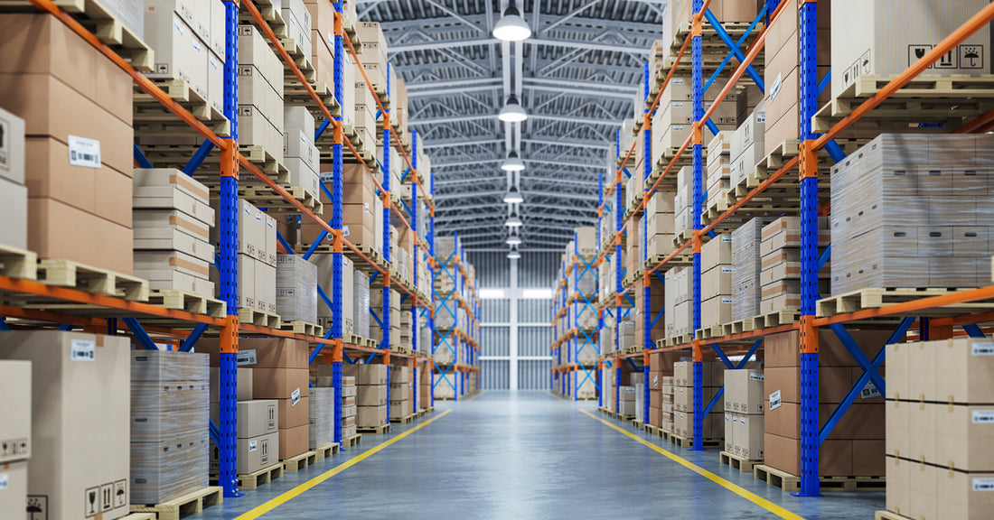 A clean, well-organized warehouse, with a clutter-free aisle and boxes neatly arranged on parallel orange-and-blue racks.