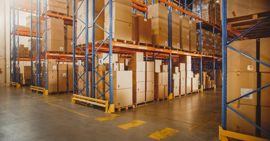 Four rows of pallet racking in a warehouse. Each rack is full of pallets of boxes. The aisles between the racks are clean.