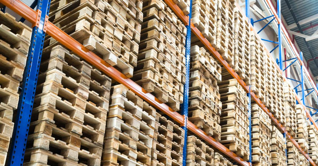 Pallet racks that extend to the ceiling of a warehouse. The racks are loaded to capacity with pallets.