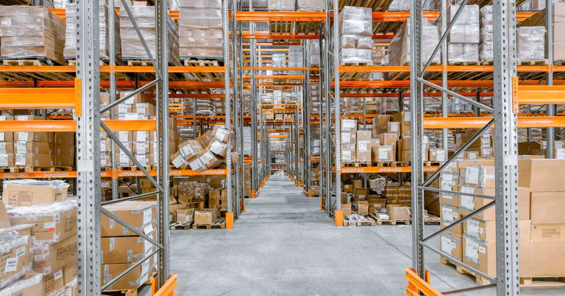 A warehouse with multiple pallet racks. The racks are full in some areas, but low in stock in other areas.