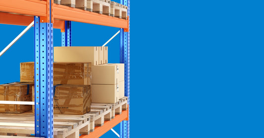 An orange-and-blue pallet racking system, with pallets and cardboard boxes on the racks, against a blue background.